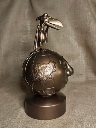 Bronze sculpture of a bird perched on a globe with a face