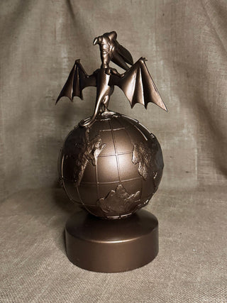 Bronze statue of a dragon on a globe against a gray background