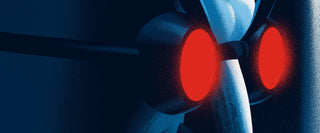 Close-up of a character wearing goggles with red lenses against a dark background