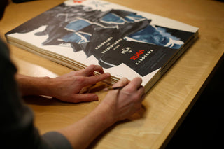 Person signing a book on a wooden table